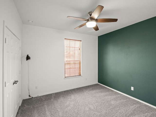 carpeted spare room with ceiling fan and baseboards