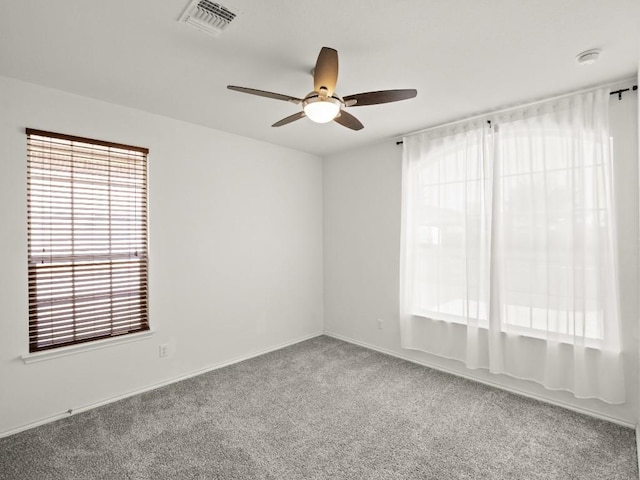 carpeted spare room featuring visible vents and ceiling fan