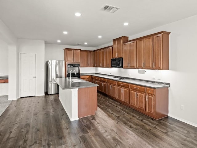 kitchen featuring black microwave, dark wood-style flooring, a sink, visible vents, and freestanding refrigerator