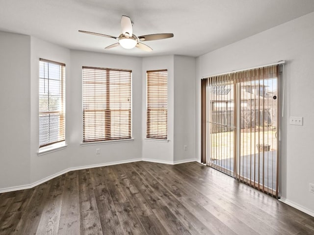 unfurnished room with dark wood-type flooring, a ceiling fan, and baseboards