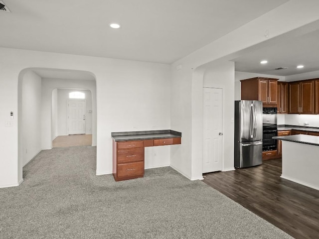 kitchen featuring arched walkways, dark countertops, recessed lighting, visible vents, and freestanding refrigerator