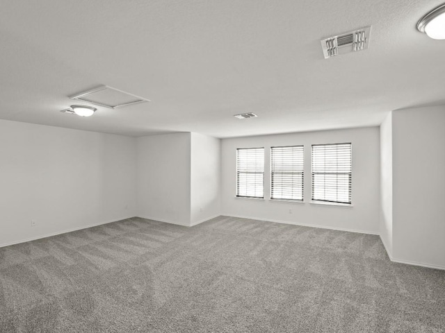 carpeted spare room with attic access and visible vents