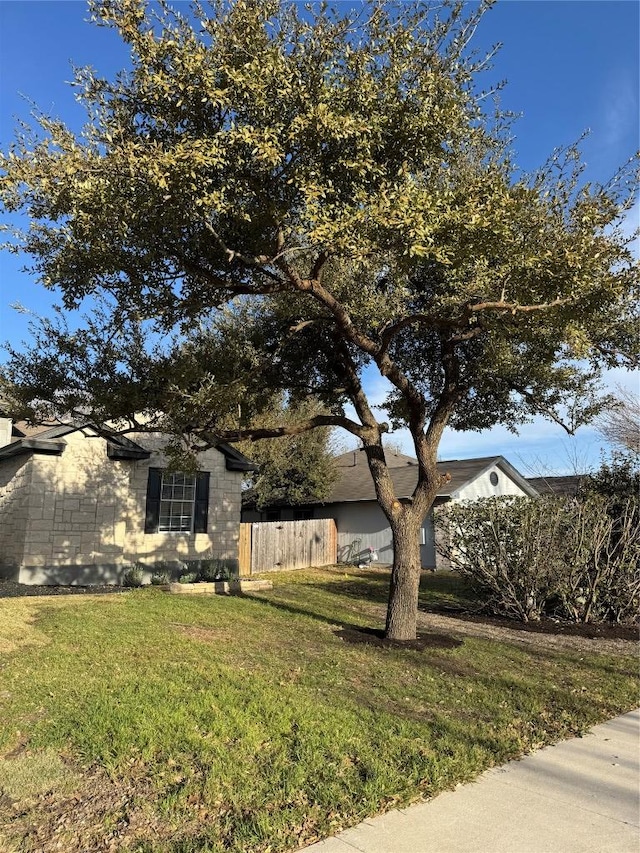 view of property exterior featuring fence and a lawn