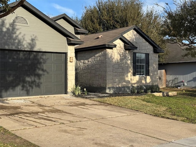 view of side of home with an attached garage, stone siding, and concrete driveway