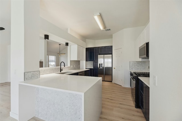 kitchen with visible vents, dark cabinets, stainless steel appliances, light wood-style floors, and a sink