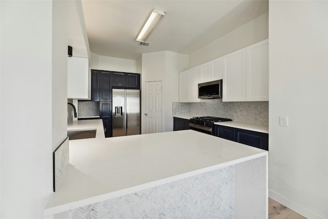 kitchen with backsplash, visible vents, stainless steel appliances, and a sink