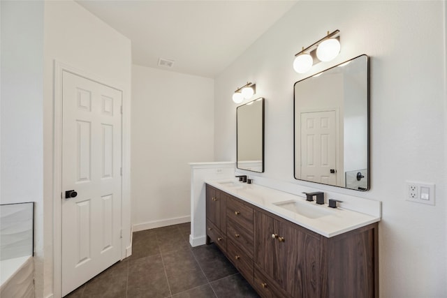 bathroom featuring baseboards, double vanity, a sink, and tile patterned floors