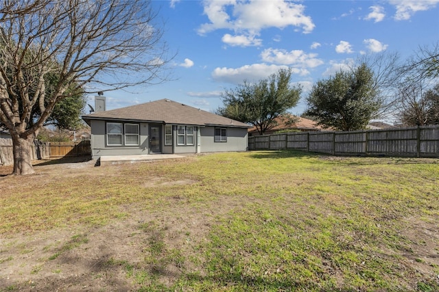 rear view of property featuring a fenced backyard, a lawn, a chimney, and a patio