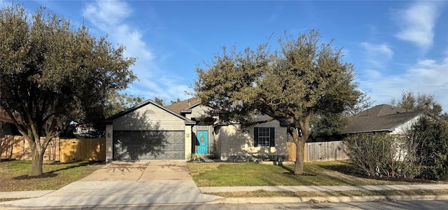 view of front of home featuring an attached garage, driveway, fence, and a front lawn