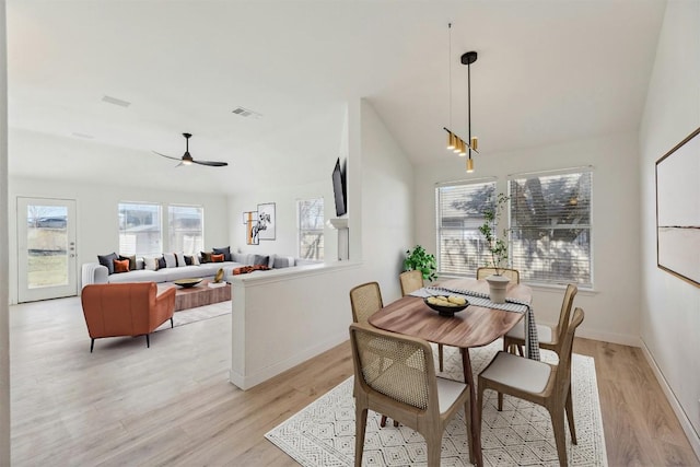 dining area featuring vaulted ceiling, light wood-style floors, visible vents, and ceiling fan