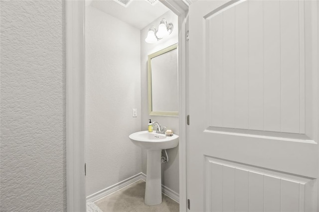 bathroom featuring baseboards and a textured wall