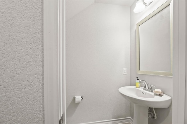 bathroom featuring baseboards, a sink, and a textured wall