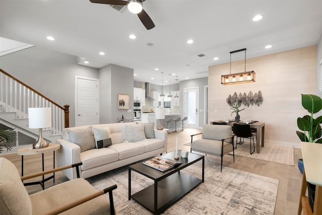 living area featuring visible vents, a ceiling fan, light wood-style flooring, stairs, and recessed lighting