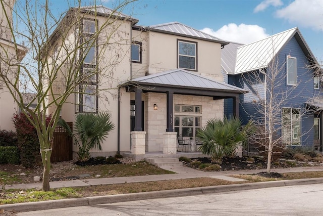 view of front facade with stone siding, metal roof, a standing seam roof, a porch, and stucco siding