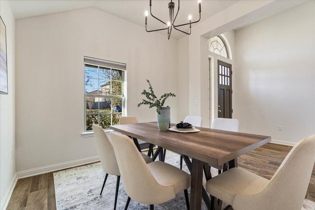 dining room with a chandelier, vaulted ceiling, wood finished floors, and baseboards