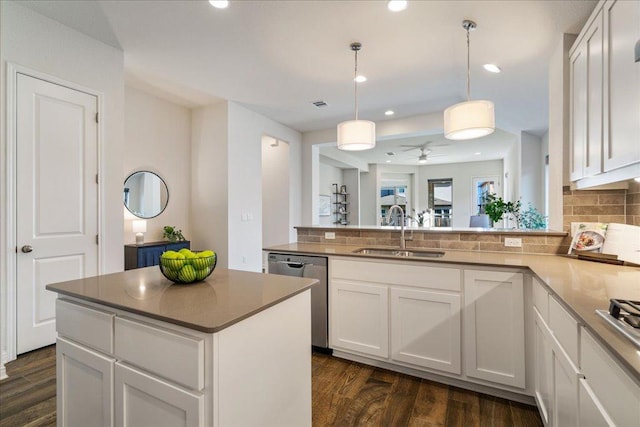 kitchen featuring backsplash, stainless steel dishwasher, white cabinets, a sink, and a peninsula