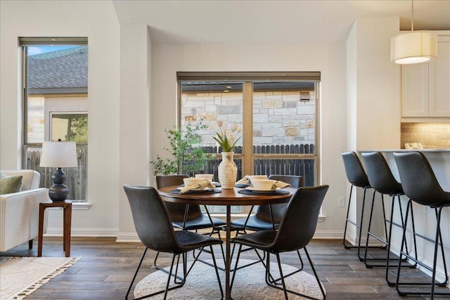 dining space featuring baseboards and dark wood-style flooring