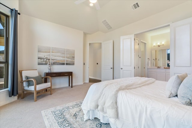 bedroom featuring lofted ceiling, light colored carpet, visible vents, ensuite bath, and baseboards