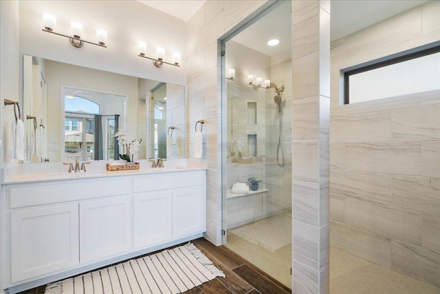 full bathroom with a walk in shower, double vanity, wood finished floors, and a sink