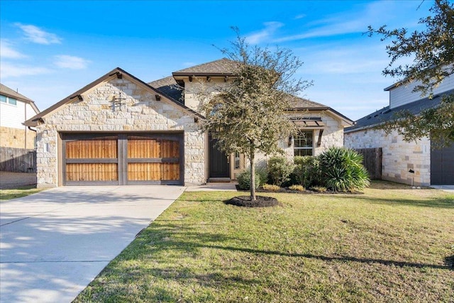 view of front of property with an attached garage, a front yard, fence, stone siding, and driveway