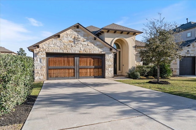 view of front of house with an attached garage, concrete driveway, stone siding, roof with shingles, and stucco siding