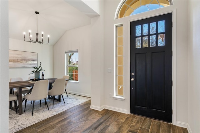 entrance foyer featuring baseboards, wood finish floors, vaulted ceiling, and a notable chandelier