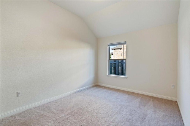 unfurnished room with vaulted ceiling, carpet floors, and baseboards