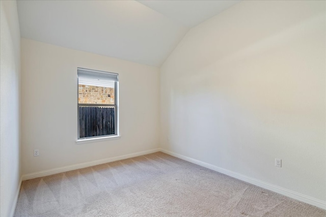 unfurnished room with carpet floors, vaulted ceiling, and baseboards