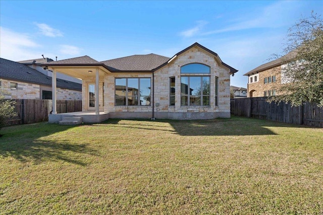 back of house featuring a patio area, stone siding, a fenced backyard, and a lawn