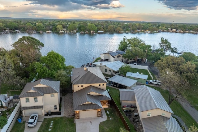 aerial view at dusk featuring a water view and a residential view