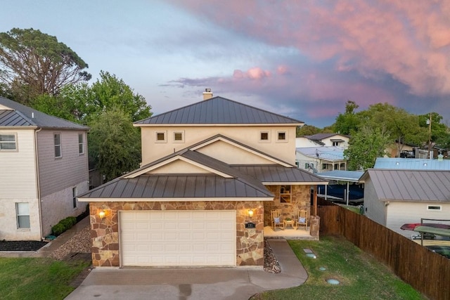 view of front of property featuring metal roof, a standing seam roof, stone siding, and driveway