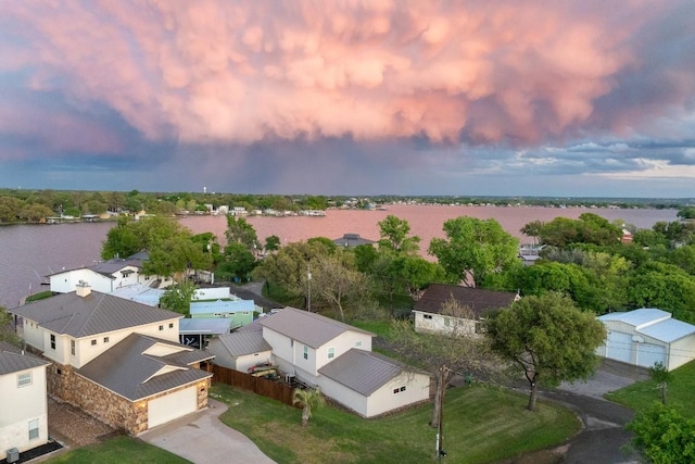 aerial view at dusk with a water view and a residential view