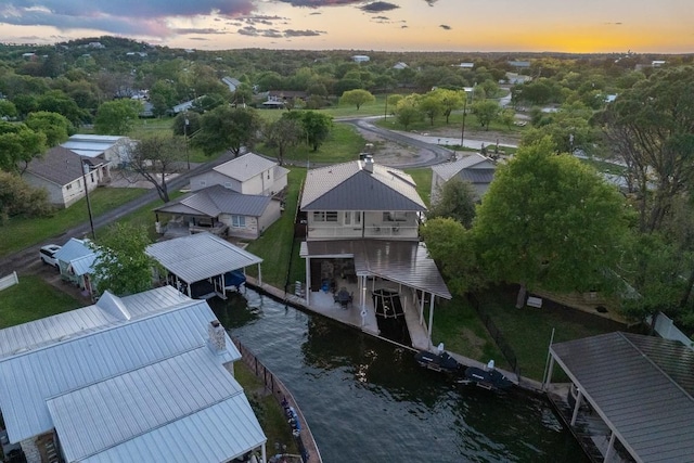 aerial view at dusk with a water view and a residential view