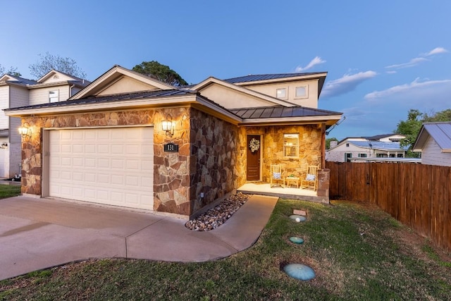 view of front of property with metal roof, a garage, fence, stone siding, and a standing seam roof