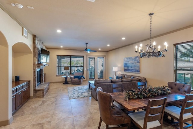 dining space with arched walkways, ornamental molding, a fireplace, and a ceiling fan