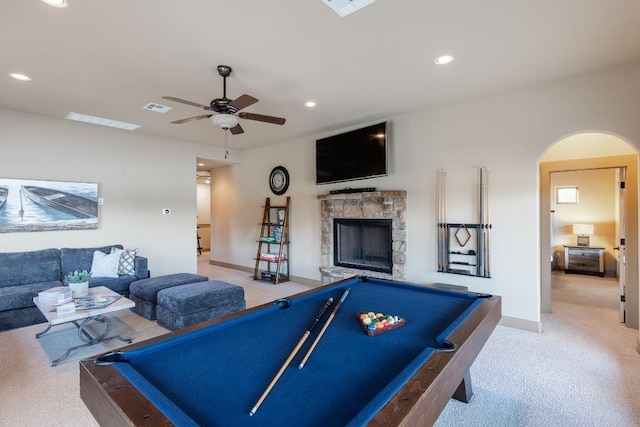 rec room featuring carpet, visible vents, arched walkways, and a stone fireplace