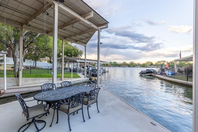 view of dock featuring outdoor dining area, a water view, fence, and boat lift