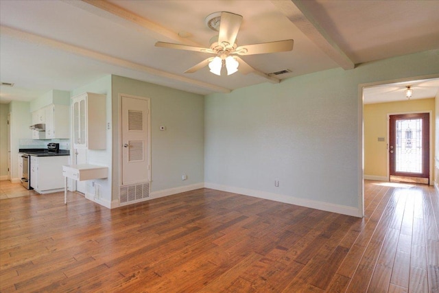 spare room featuring beamed ceiling, wood finished floors, visible vents, and baseboards