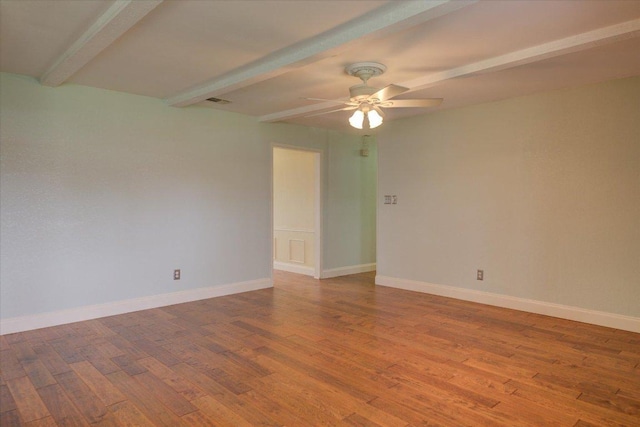 unfurnished room featuring wood finished floors, beam ceiling, and baseboards