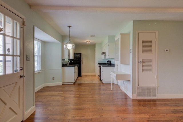 kitchen featuring wood finished floors, a sink, white cabinetry, appliances with stainless steel finishes, and dark countertops