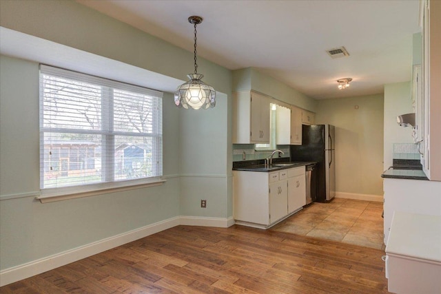 kitchen with dark countertops, light wood finished floors, baseboards, and visible vents