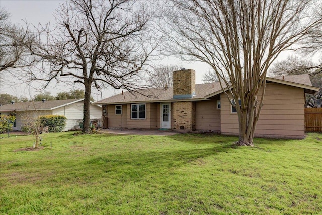 back of house featuring a patio area, a chimney, fence, and a lawn