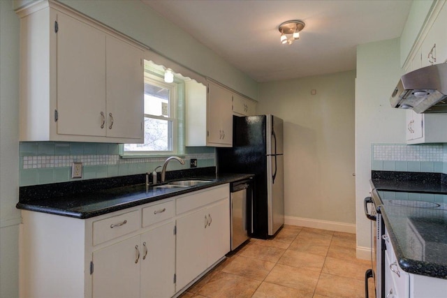 kitchen with tasteful backsplash, appliances with stainless steel finishes, a sink, baseboards, and exhaust hood