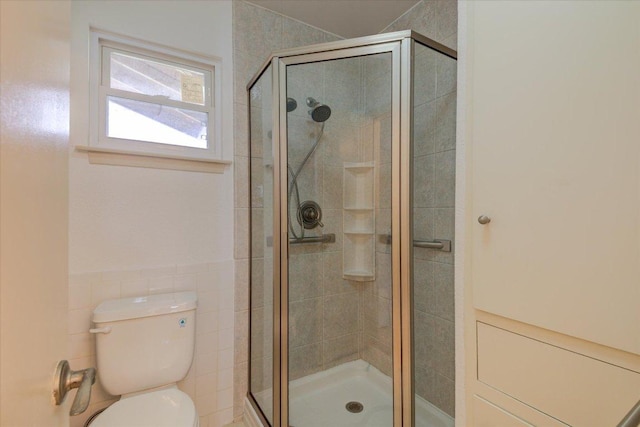 full bath featuring a stall shower, tile walls, and toilet