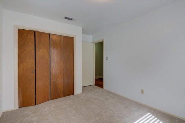 unfurnished bedroom with a closet, visible vents, and carpet flooring