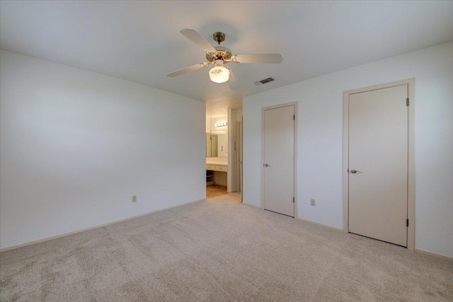 unfurnished bedroom featuring a ceiling fan, light colored carpet, visible vents, and ensuite bathroom