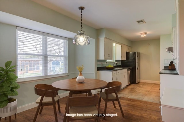 dining space featuring visible vents, light wood-style flooring, and baseboards