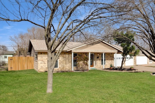 view of front facade with a garage, brick siding, a front lawn, and fence