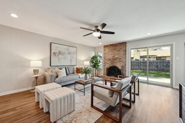 living area with recessed lighting, a fireplace, wood finished floors, a ceiling fan, and baseboards