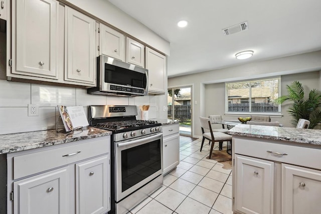 kitchen featuring stainless steel appliances, light stone countertops, visible vents, and light tile patterned floors